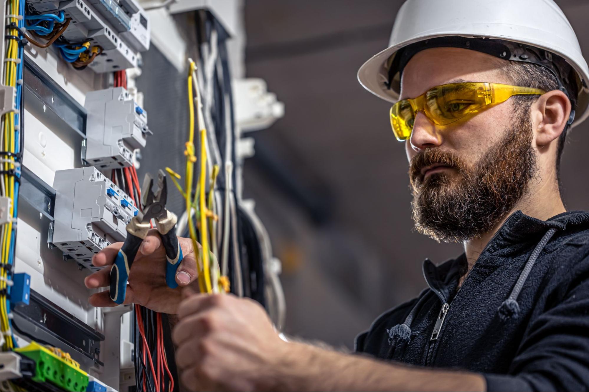 Image of a professional electrician wearing safety gear and holding electrical tools ready to provide 24-hour emergency service.