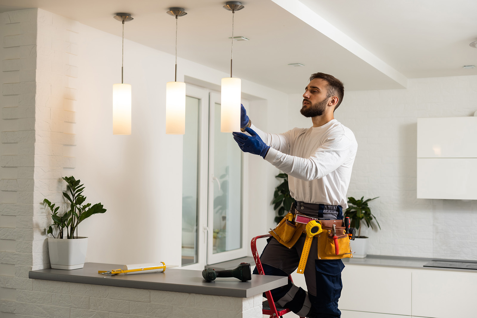 A residential electrician carefully installs lights in a new home, ensuring proper wiring and connections for safe and functional illumination.