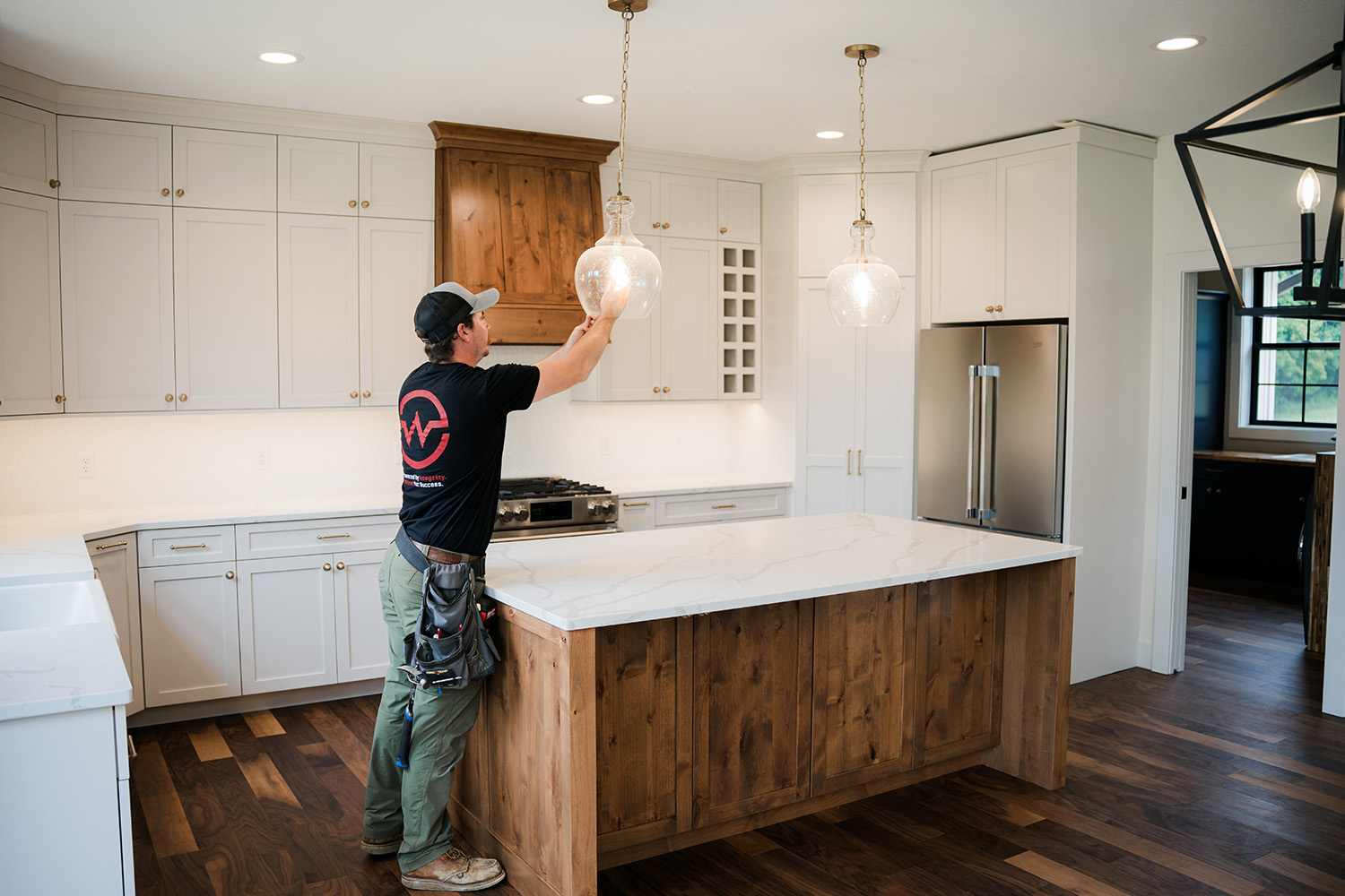 Webster electric installing a light fixture over a beautiful kitchen island.