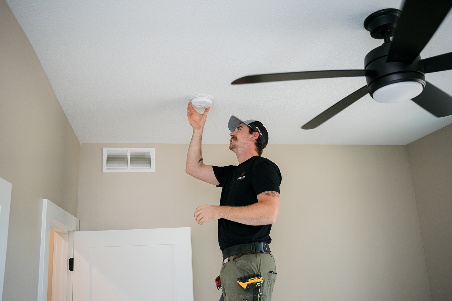 Webster Electric technician providing same-day residential electrical service by installing a smoke detector in a West Michigan home.
